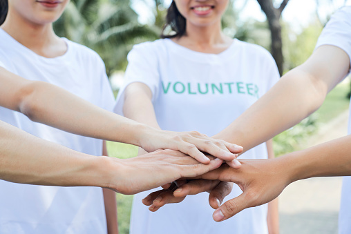Close-up image of volunteers stacking hands to express support and unity before starting work