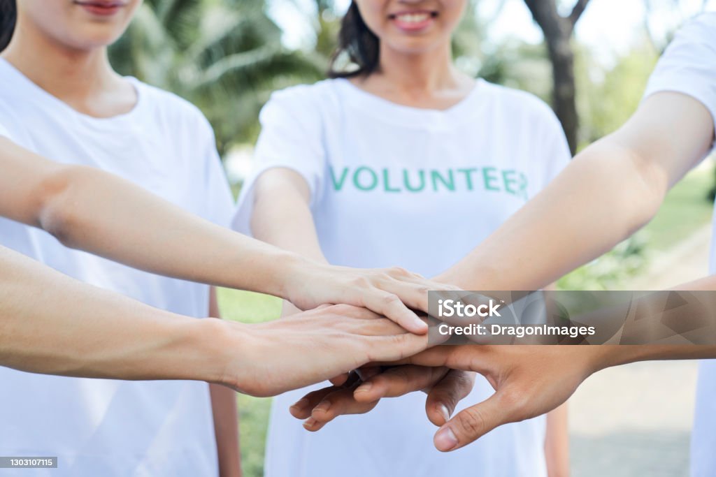 Volunteers standing hands Close-up image of volunteers stacking hands to express support and unity before starting work Volunteer Stock Photo
