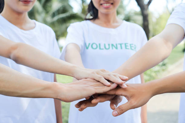 volunteers standing hands - volunteer imagens e fotografias de stock