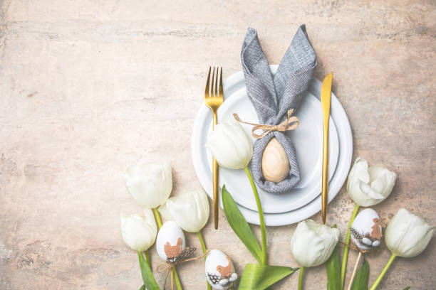 istock Easter holiday table setting with bunny  from egg on white plate and tulips flowers.  Gray concrete table, top view with copy space for text. Happy Easter background 1303109652