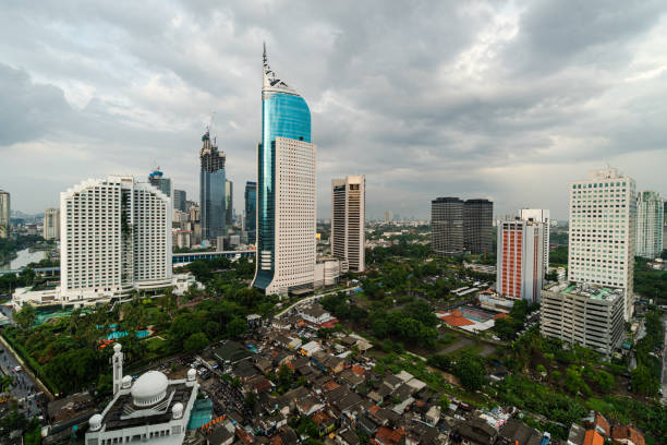 Dramatic sky over Jakarta downtown skyline where modern skyscrapers contrasts with poor residential district in Indonesia capital city Dramatic sky over Jakarta downtown skyline where modern skyscrapers contrasts with poor residential district in Indonesia capital city jakarta slums stock pictures, royalty-free photos & images