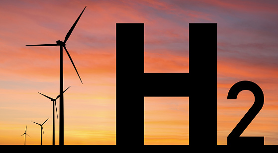 Silhouettes of Hydrogen symbol and wind turbines. Getting green hydrogen from renewable energy sources