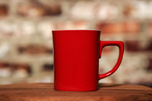 Red coffee cup on table with brick background