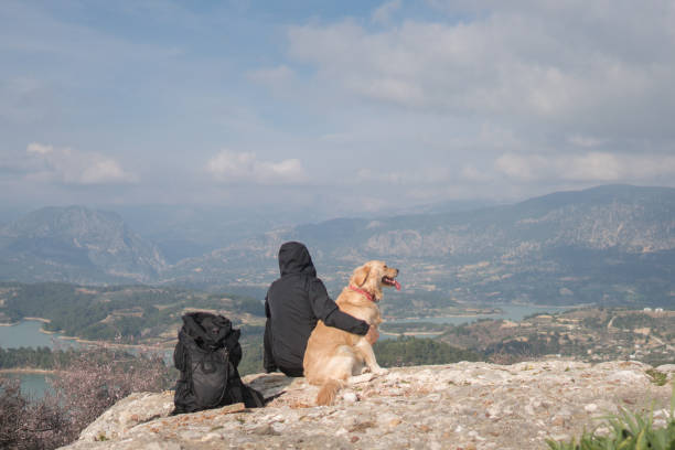 istock Man sitting wit his dog on mountain peak . 1303122344