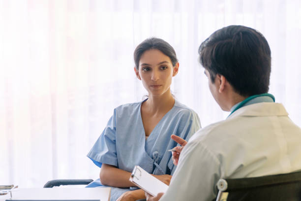 istock Doctor man wear uniform with pen and stethoscope sitting in office while talking about problem health patient woman fell friendly. Patient young woman listen advice doctor. Health-care concept. 1303122492