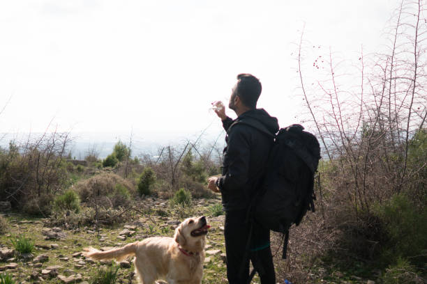 istock Man with a dog in the mountain drinking water. 1303123414