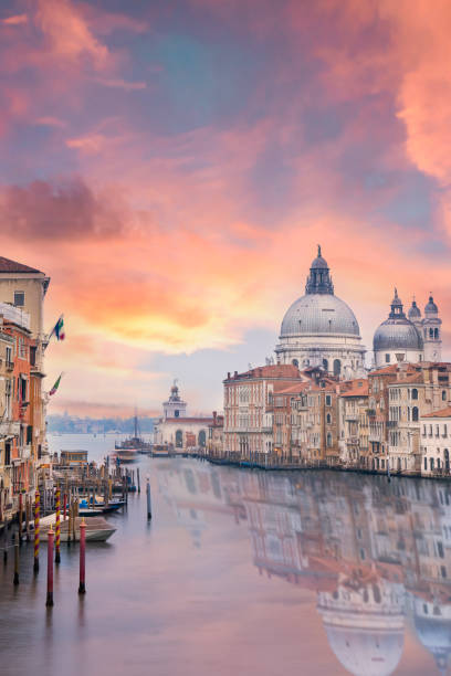 Stunning view of the Venice skyline with the Grand Canal and Basilica Santa Maria Della Salute in the distance during a dramatic sunrise. stock photo