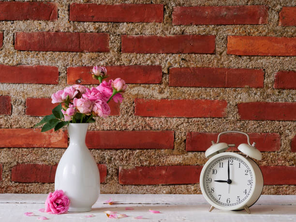 istock Vintage clock with pink roses against brick wall background. 1303125603