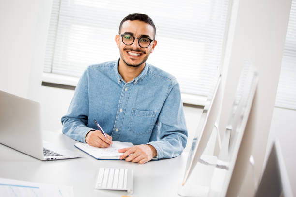 istock Happy arab businessman smiling while looking at camera in office 1303130737