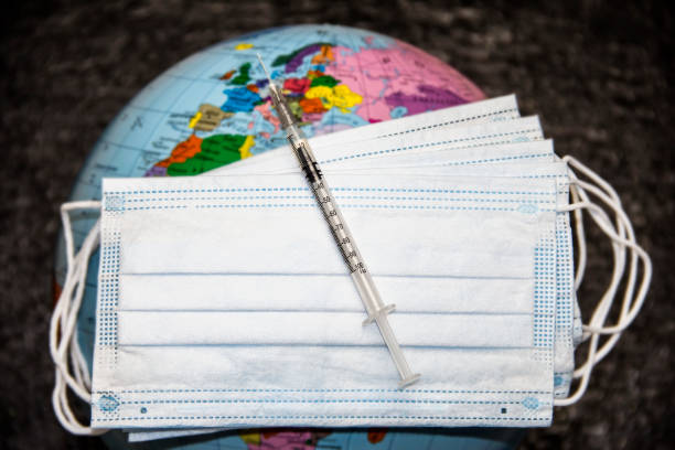 istock Medical syringe on masks on the globe. 1303131523