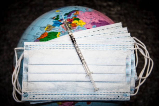 istock Medical syringe on masks on the globe. 1303131572