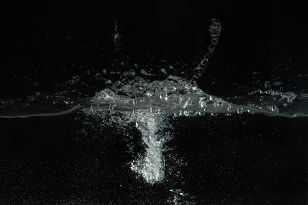 istock Water splashing as it's poured into aquarium tank, black background 1303131897