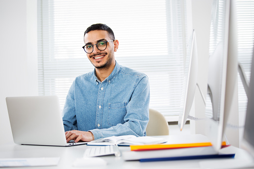 Happy handsome arab businessman smiling while looking at camera in office