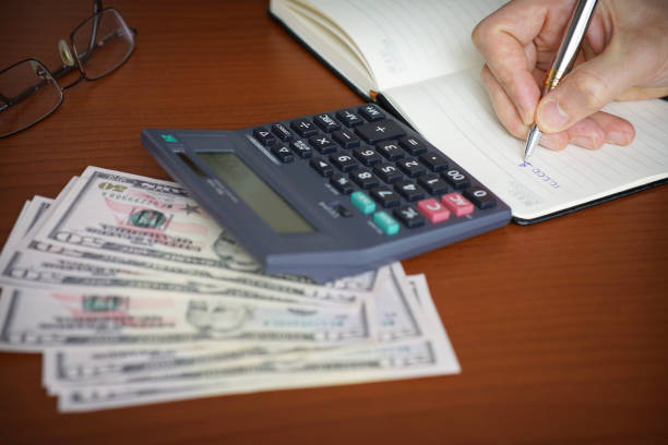 istock Business Man Using Pen And Calculator On Desk 1303133034