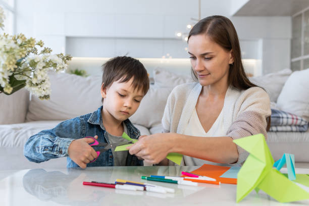 istock Mother and son cutting colored paper with scissors 1303133596