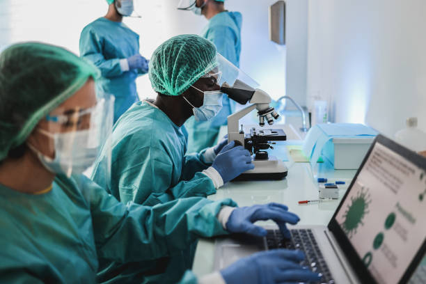 현대 실험실 병원 내부 현미경 및 노트북 컴퓨터와 함께 작업 헤이즈마트 정장에 다인종 의학 과학자 - 초점 아프리카 남자 얼굴 - 의료 연구 뉴스 사진 이미지