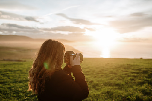 Young woman using a DSLR camera at sunset