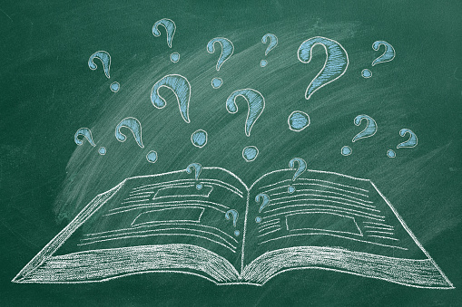 Opened book and question marks in chalk on a green chalckboard. Concept of Help, About, Info, Education, Learning or others