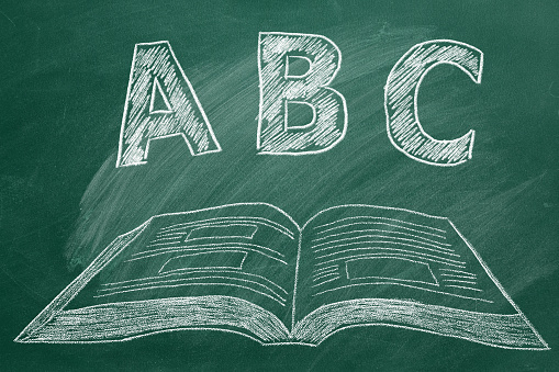 ABC letters with open book in chalk on a green chalckboard. Elementary school.