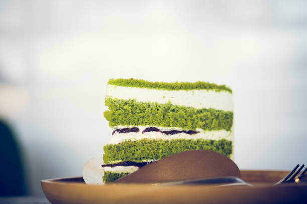 A piece triangle pandan layer cake filled with cream and red beans. Selective focus