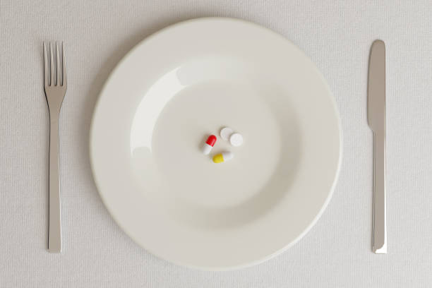 istock Top view of a plate with pills next to a knife and a fork on a white background. 3d illustration. 1303141292
