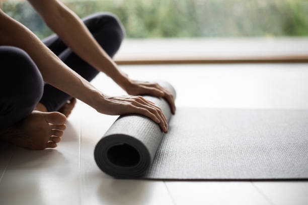 istock Woman rolling up exercise mat and preparing doing yoga or workout 1303143659