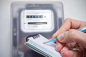 Woman with pen and notepad writes the electricity meter readings. Payment of utility services.