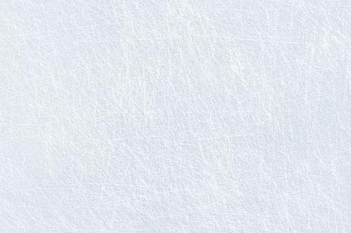 Ice background texture and snow surface with marks and lines from skating. Ice hockey rink, arena or stadium from top view. Light blue frost wallpaper. Rough frosty traces from winter sport. Icy lake.