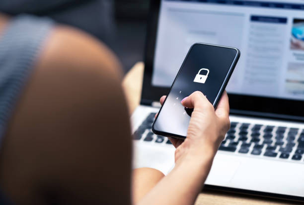 Phishing, mobile phone hacker or cyber scam concept. Password and login pass code in smartphone. Online security threat and fraud. Female scammer with cellphone and laptop. stock photo