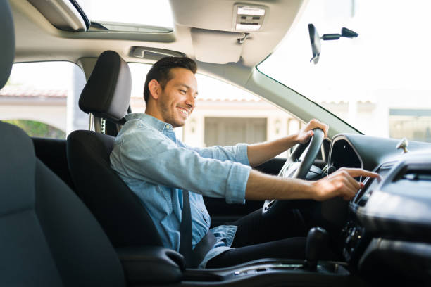 Attractive male driver using the GPS navigation map on the car Handsome man in his 30s sitting in the driver's seat and smiling. Taxi driver listening to music on the car and changing the radio station driving photos stock pictures, royalty-free photos & images