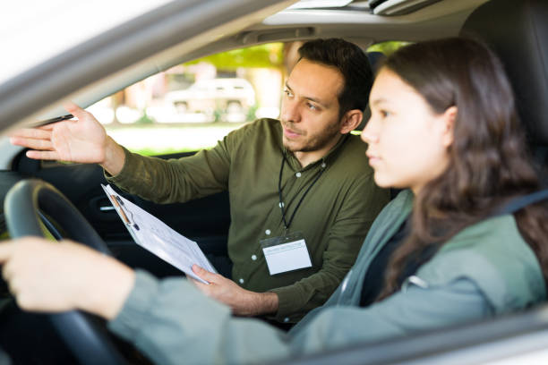 istock Hispanic instructor teaching a teen girl how to drive 1303145943