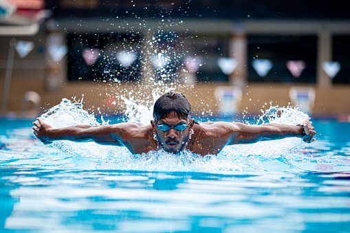 Asian Indian swimmer practicing in swimming pool with butterfly style