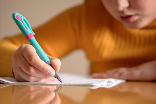 Child writing a schoolwork in a notebook with a fountain pen