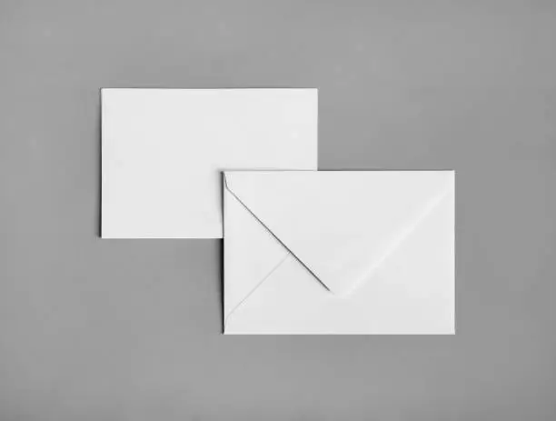 Two blank paper envelopes on gray paper background. Back and front. Flat lay.