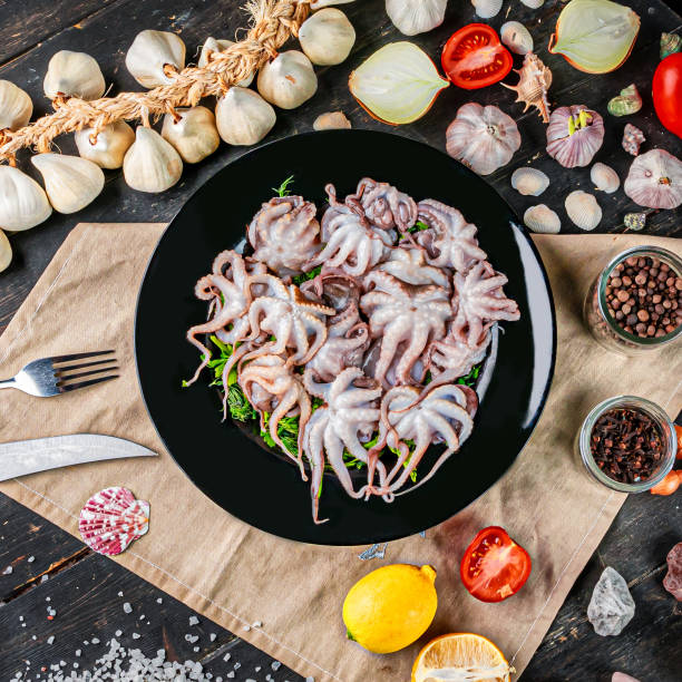 istock Raw baby octopus in a black plate 1303150849