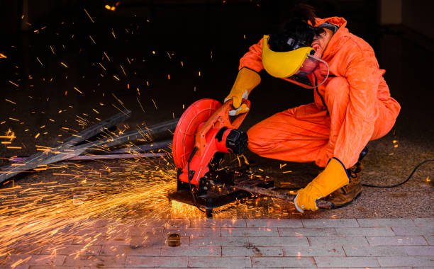Asian man worker wearing yellow protective mask and fire protection gloves with personal protection equipment sitting cutting steel Asian man worker wearing yellow protective mask and fire protection gloves with personal protection equipment sitting cutting steel by fiber circular saw machine in factory. grinding metal power work tool stock pictures, royalty-free photos & images