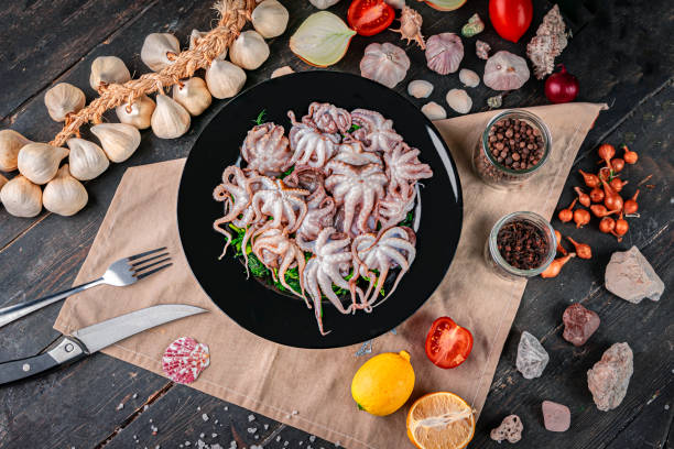 istock Raw baby octopus in a black plate 1303151826