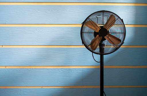 Black old fan on a blue background with contrasting lights and shadows.