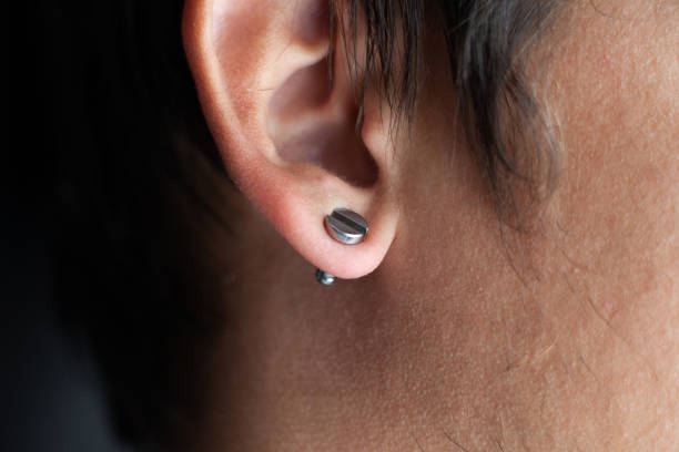piercing in a man's ears closeup,\near tunnel.
