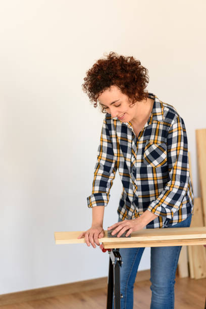 istock Woman sanding wood on a workbench with white background indoor. 1303154607