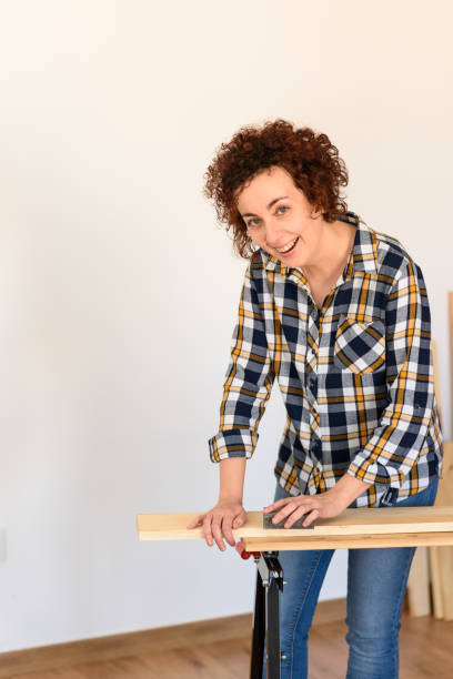 istock Woman sanding wood on a workbench with white background indoor. 1303154636