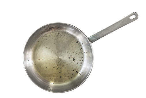 Skillet after used, isolated modern stainless steel skillet or pan with burning mark, used cooking oil in pan and burning small pieces of food. Isolated image on white background. Top view burned pan.