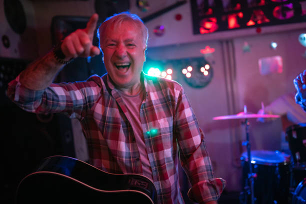 istock Senior man playing guitar on stage with his band 1303156636