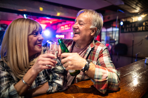 Senior couple sitting at bar counter and having fun date night in night club