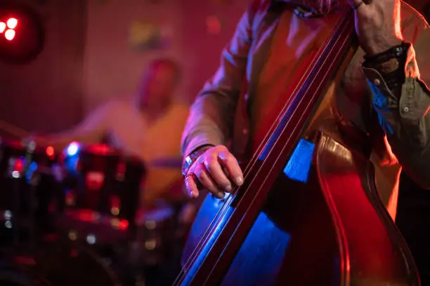 Photo of Senior man playing double bass on stage with his band on gig