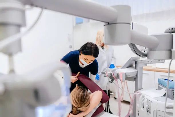 Nurse with a protective face mask preparing a patient for the breast examination