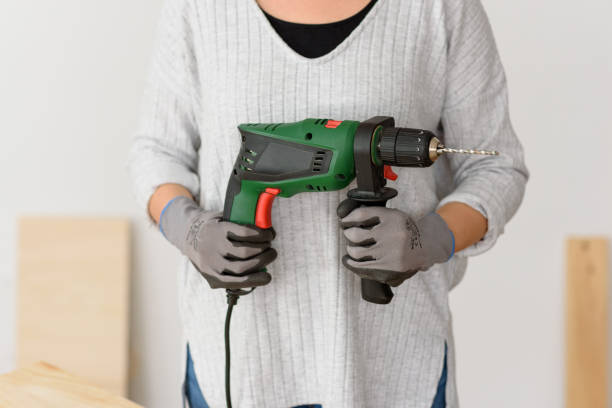 istock Young woman holding a drill, ready to make home improvements 1303158400