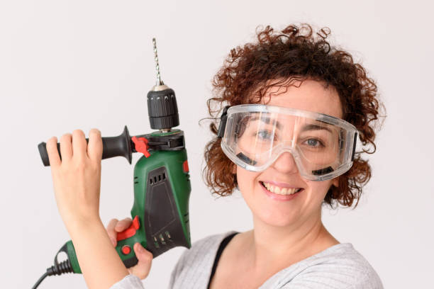 istock Young woman holding a drill, ready to make home improvements 1303158440