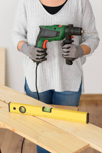 istock Young woman holding a drill, ready to make home improvements 1303158512