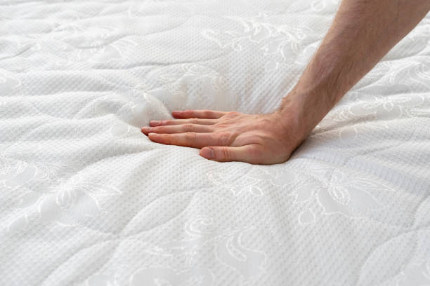 Orthopedic memory foam mattress with soft topper Close up view of cropped hand pressing on soft orthopedic memory foam mattress. Man testing comfortable bed with ecologic material on hypoallergenic topper. Healthy sleeping and advertising concept latex stock pictures, royalty-free photos & images